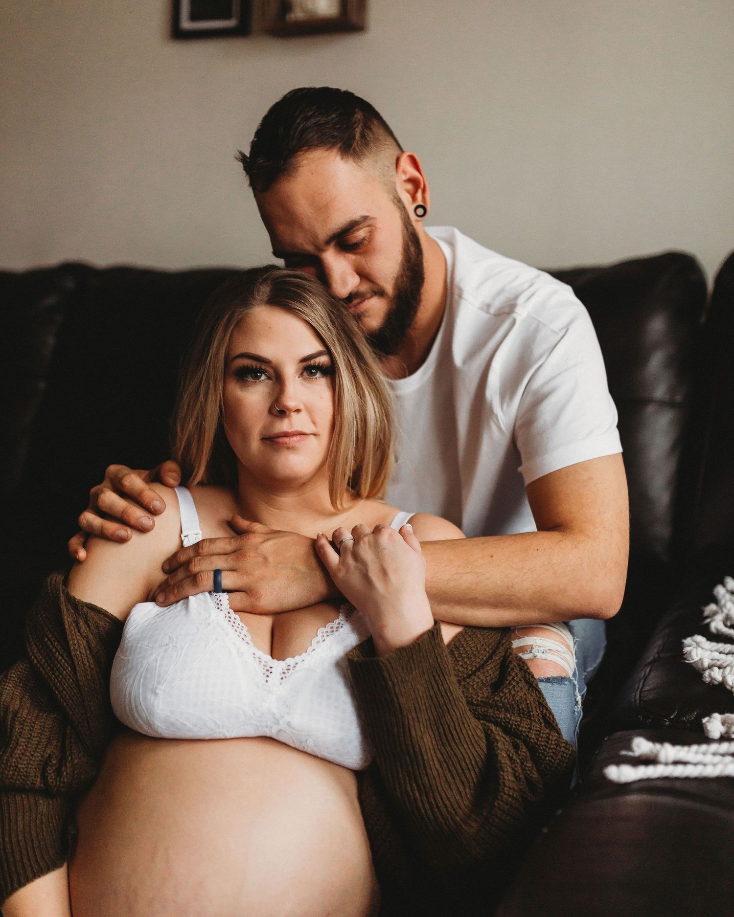 Cozy maternity portrait showing loving embrace on leather sofa.
