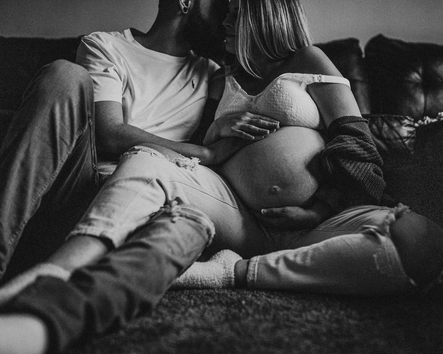 Artistic black and white pregnancy portrait on leather sofa.