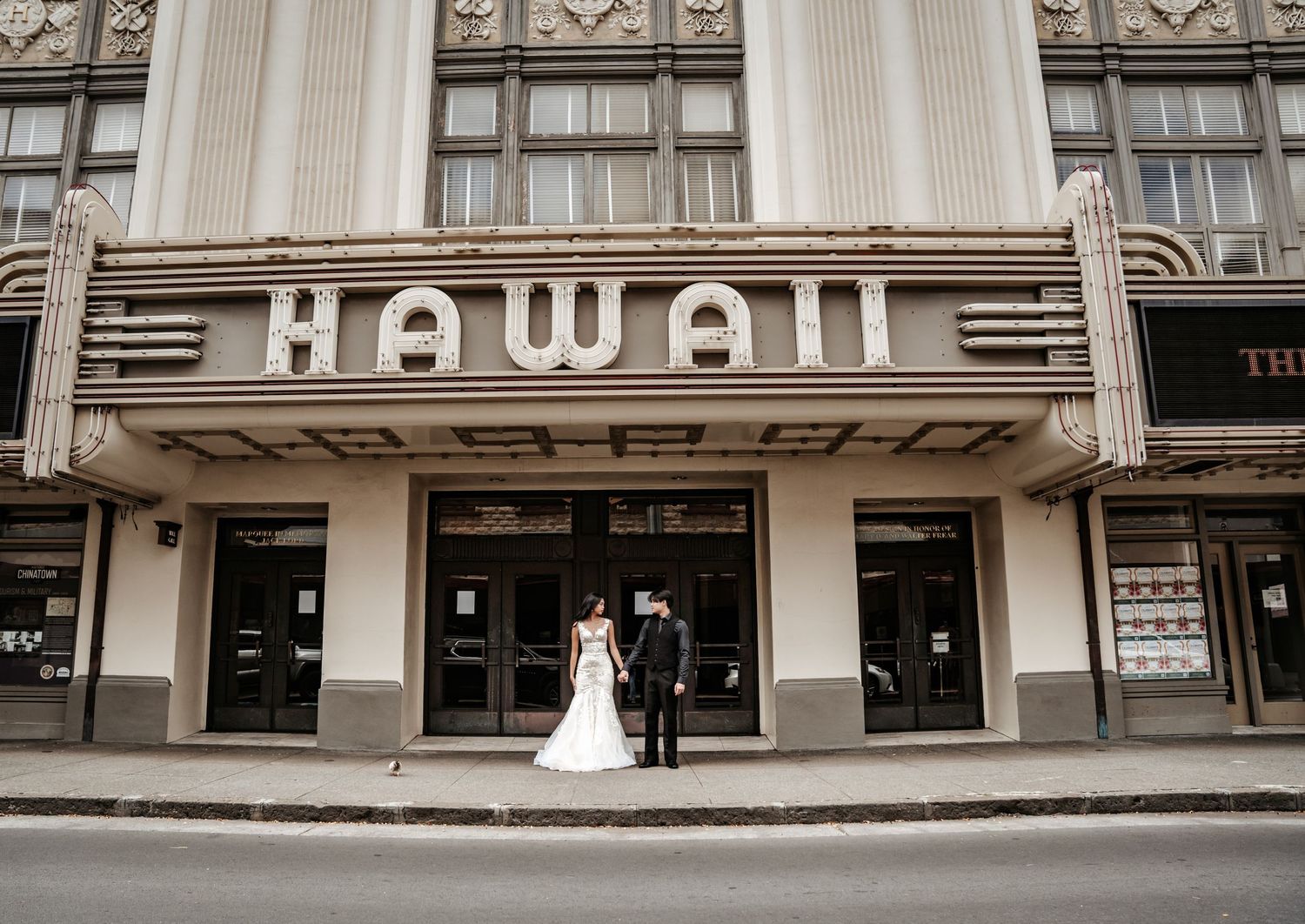 Historic Hawaii Theater facade with couple standing beneath classic art deco signage.