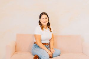 Person lounging comfortably on pink sofa in bright minimalist setting.