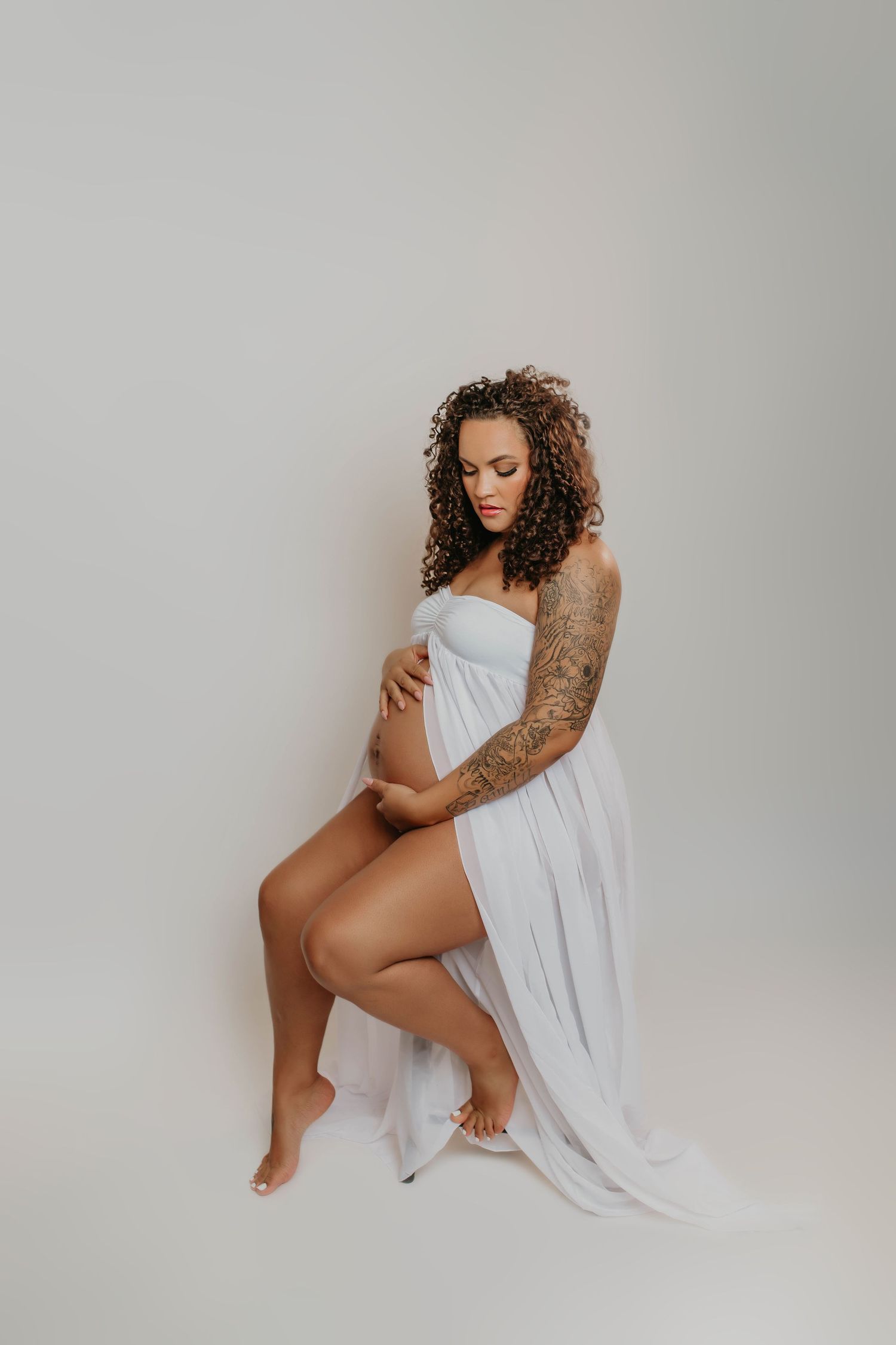 Studio portrait of woman in white fabric against grey background.