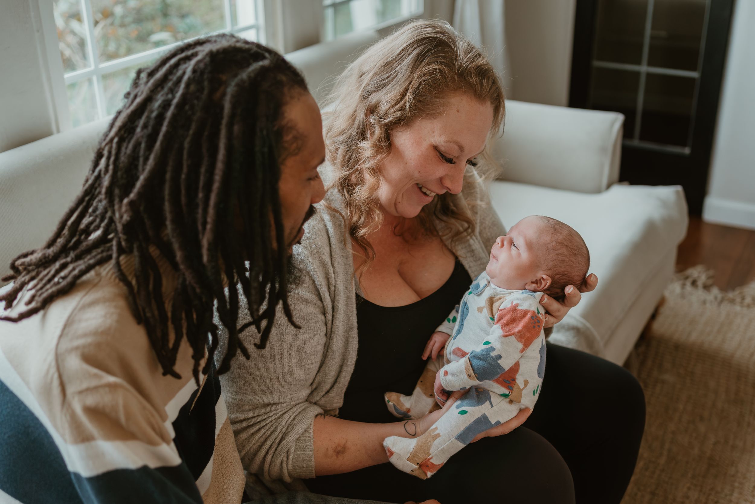 An intimate family moment with parents cradling their newborn baby on a couch.
