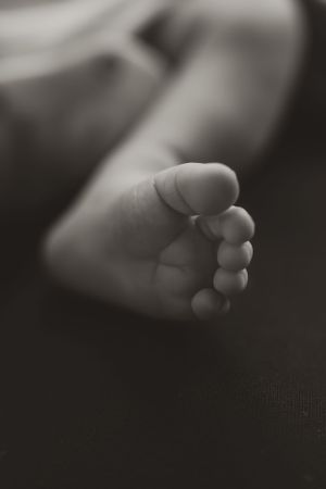 Black and white macro shot of tiny newborn baby toes in soft focus.