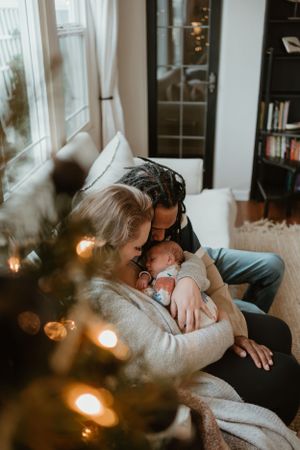 Intimate family moment captured in warm lighting with Christmas decorations twinkling in the background.