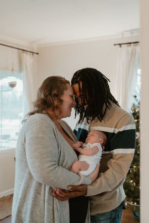 A family shares tender moments with their newborn baby in their living room.