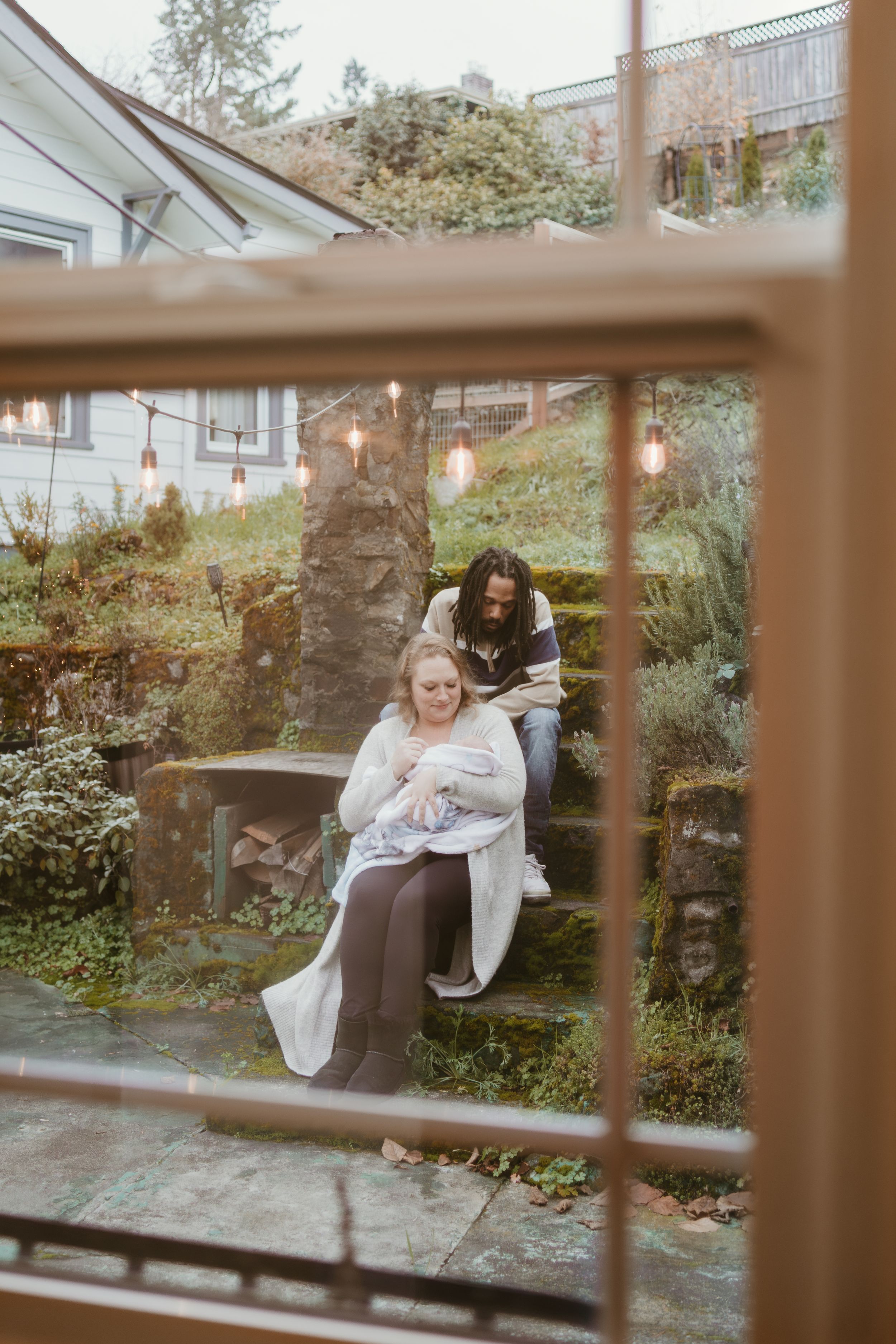 Family photoshoot through window panes with natural outdoor scenery in background.