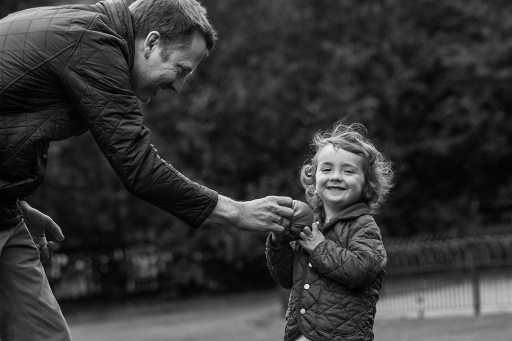 Dad and his kids playing with a ball on family photoshoot in London