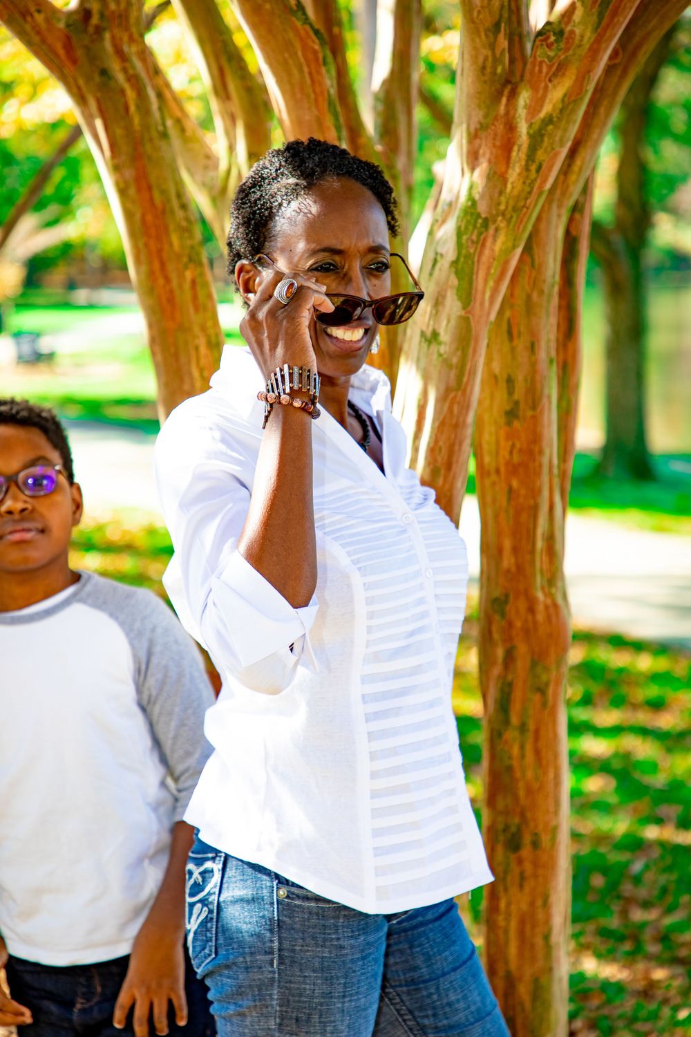 A candid moment captured in a park with trees showing genuine laughter and joy.