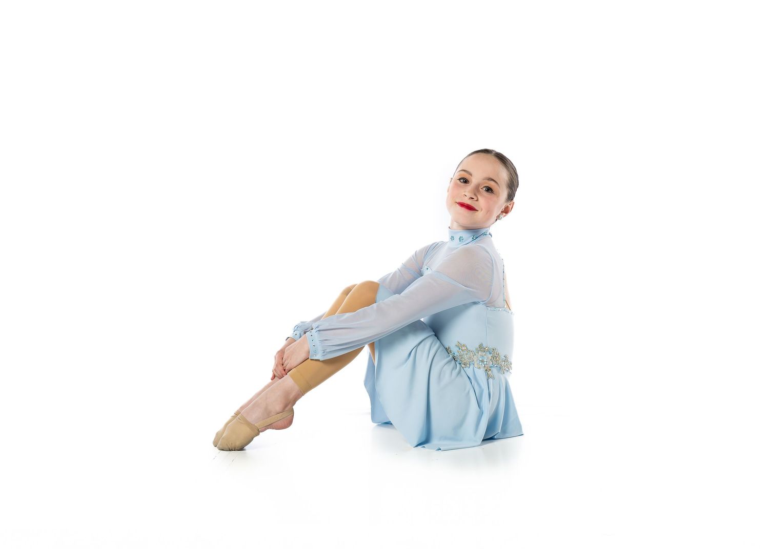 A dancer in a blue lyrical dress sitting on a white backdrop