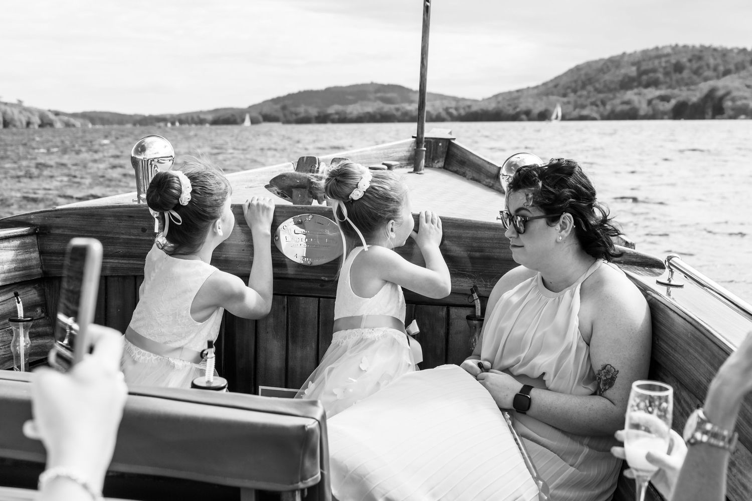 flower girls lean over the front of the boat taking in the views of Lake Windermere and the fells in the distance