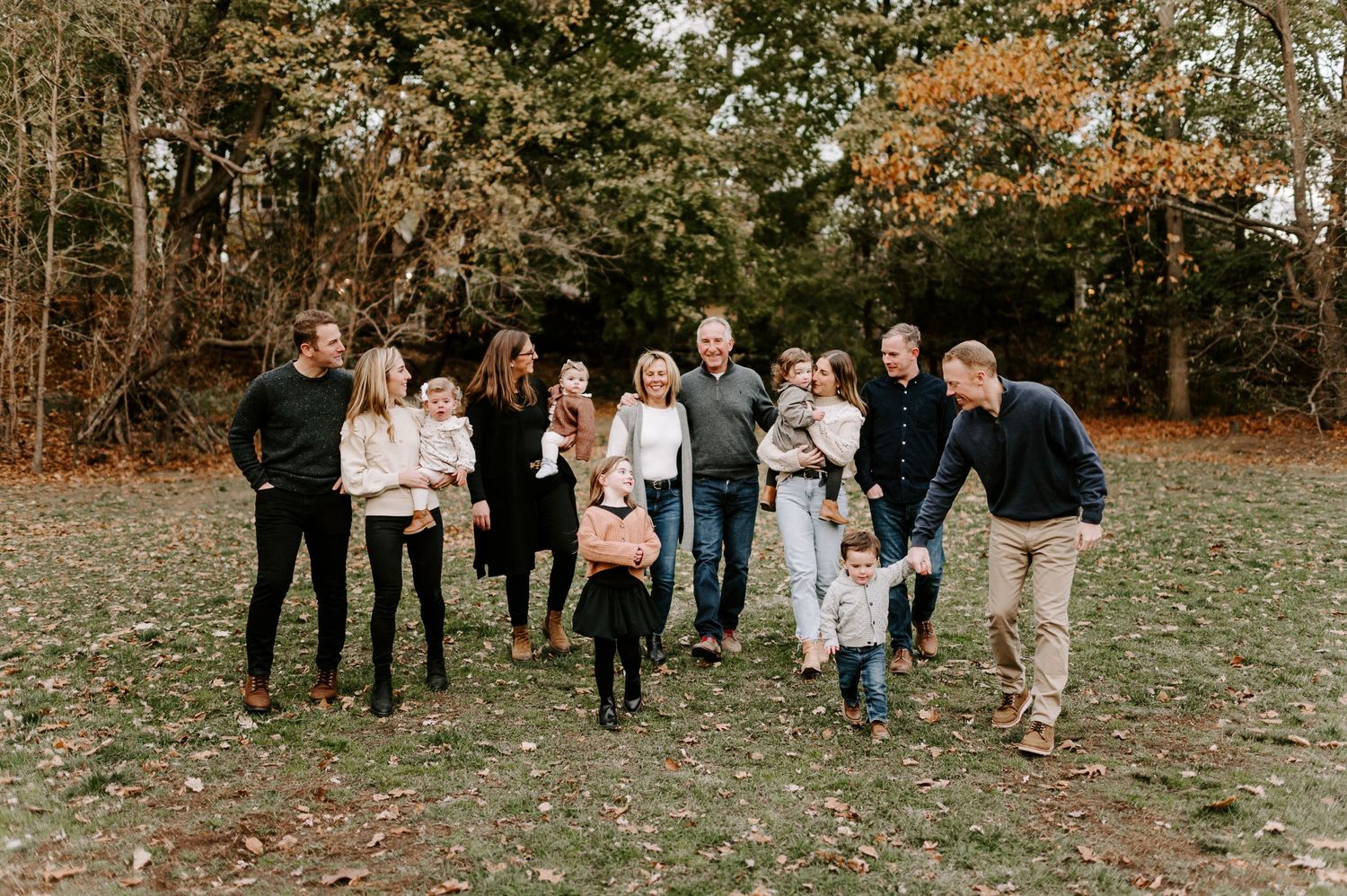 Wedding guests walking through autumn foliage during outdoor celebration.