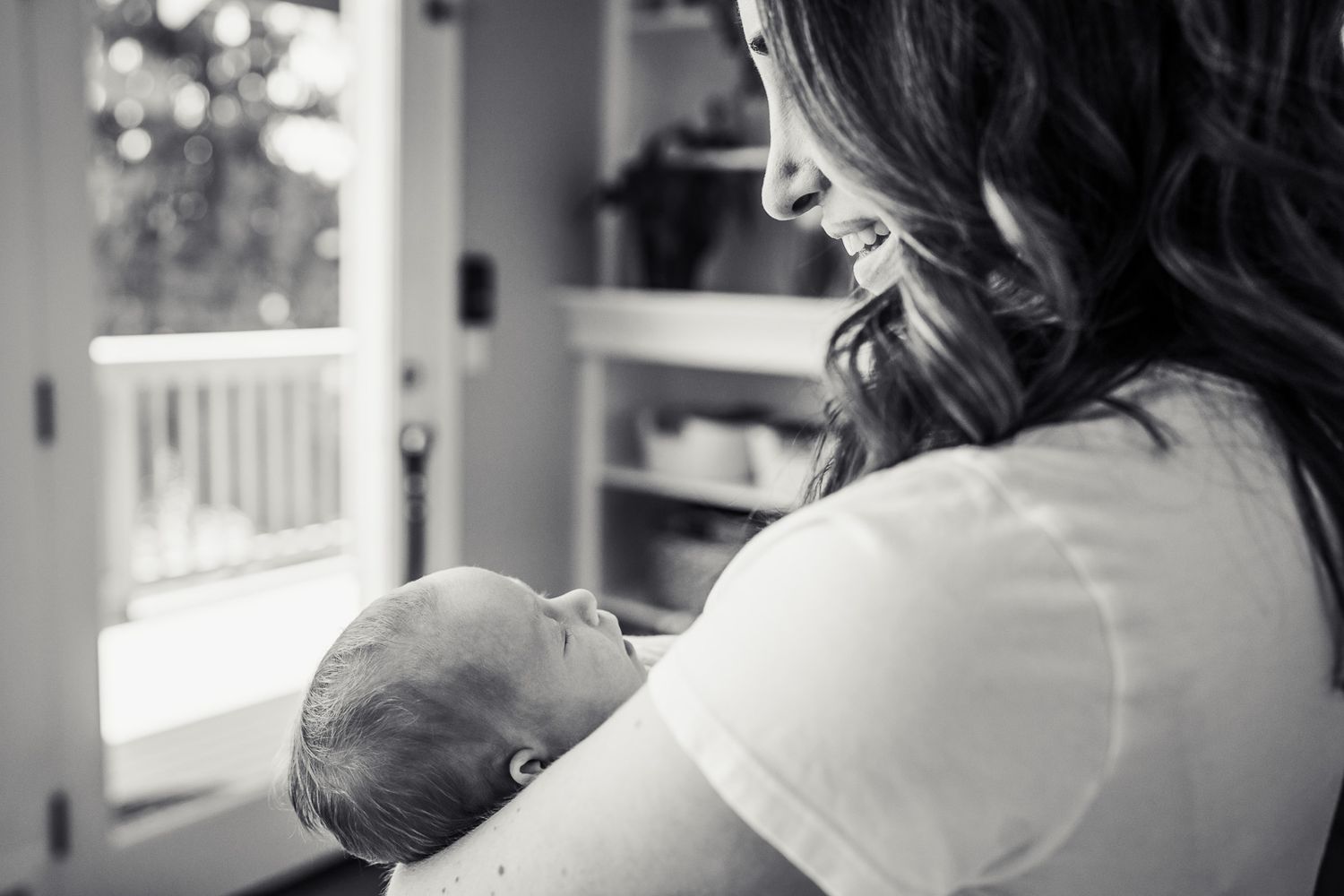 Black and white photo of mom lovingly looking at newborn daughter.