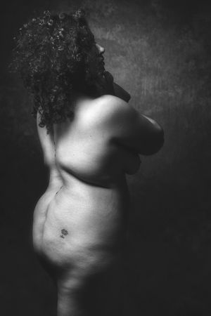 volslank model in zwart wit naakt in de studio met de rug naar de camera