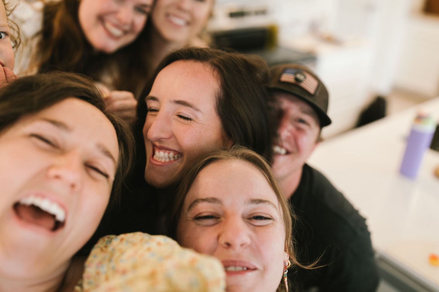 Close-up candid shot of friends laughing together indoors.