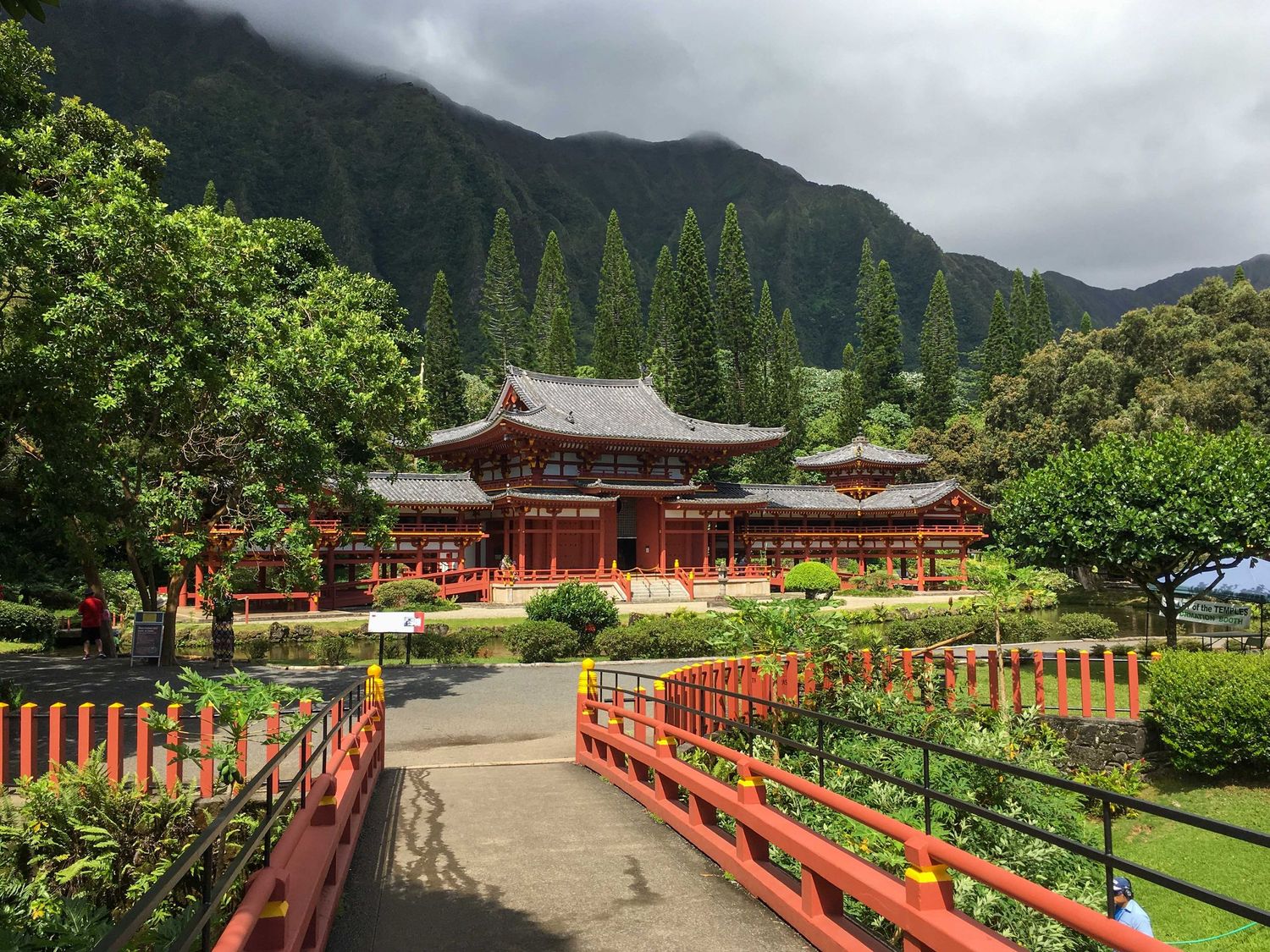 The red Byodo-In Buddhist temple with its reflection pond sits beneath misty mountains in the lush Valley of the Temples, Hawaii.