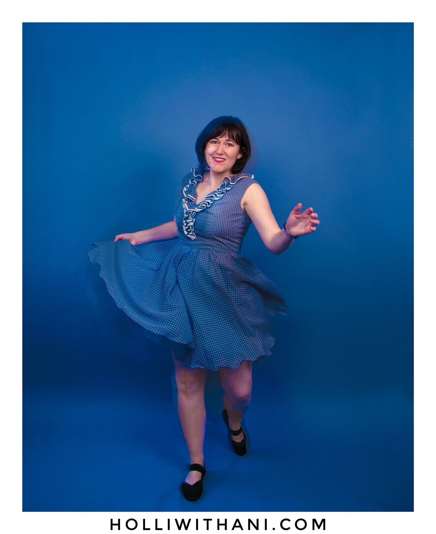 Woman dancing in gray dress with a dark blue backdrop in vibrant color.