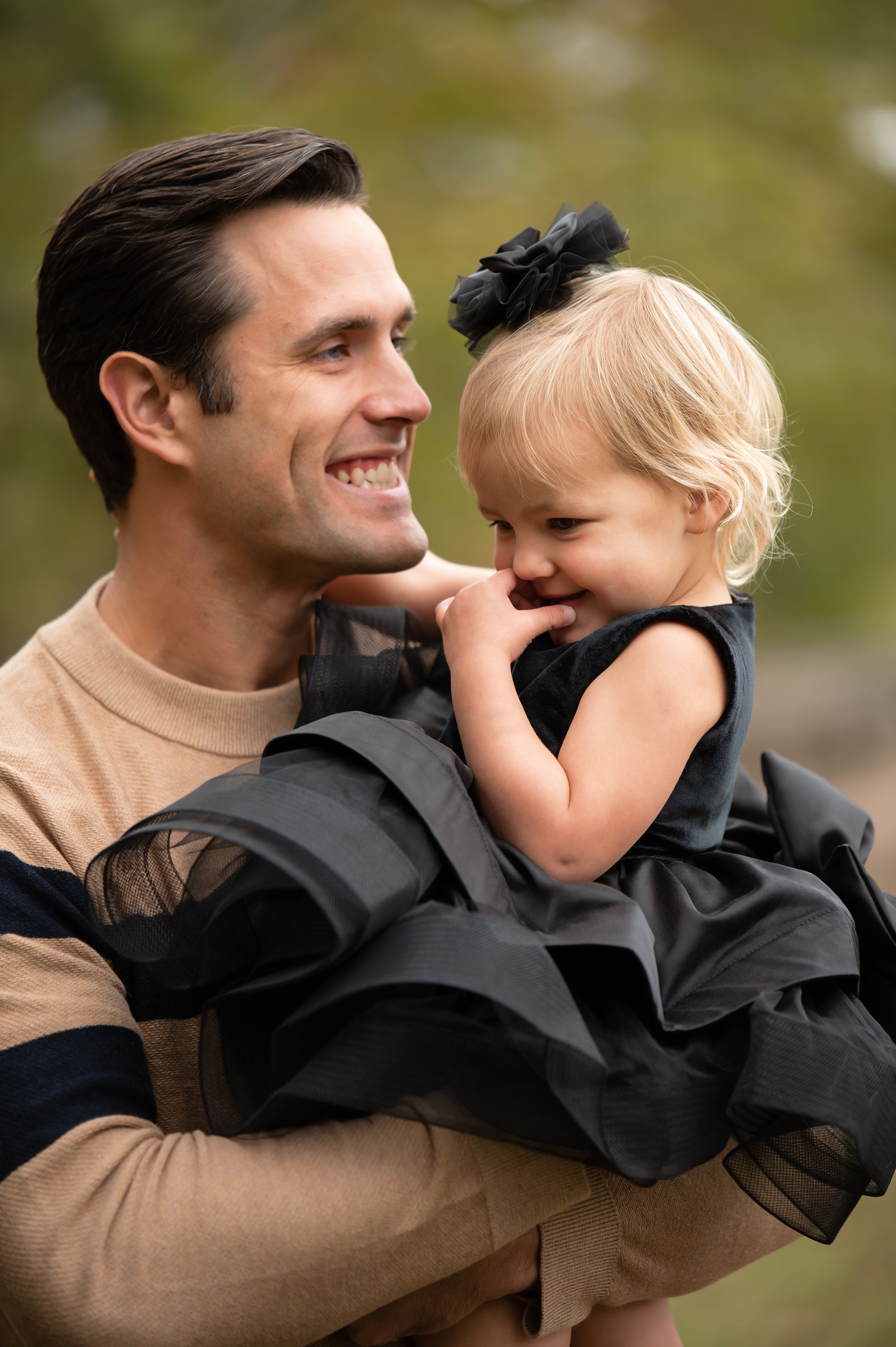 A tender moment captured outdoors with autumn colors in the background.