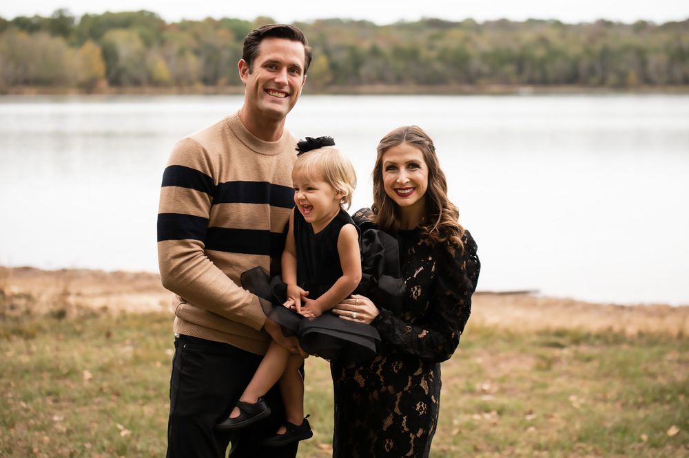 A family poses together on an autumn day by a serene lake.