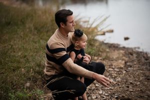 An intimate parent-child moment shared while sitting by a lake.