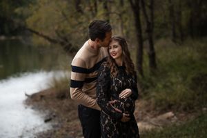 A couple shares an intimate moment outdoors by a lake during autumn.