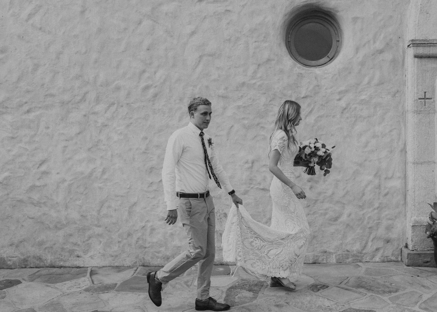 Couple walking along a white wall in minimalist black and white photography.