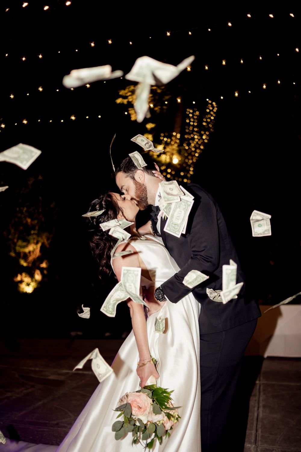 fun bride and groom kissing while money is thrown around them photographed by missouri wedding photographer