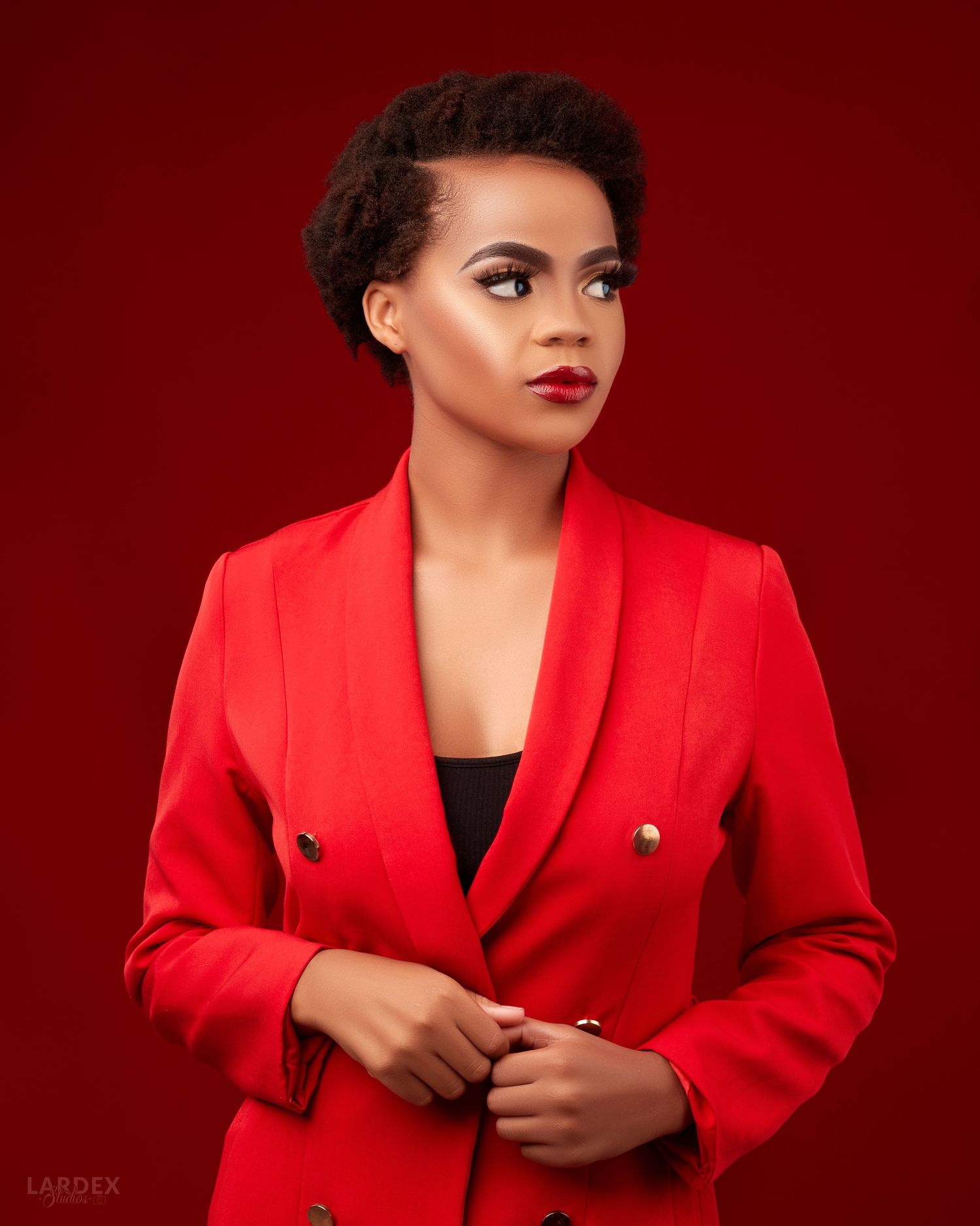 Professional studio portrait of woman in vibrant red blazer against dark red background.