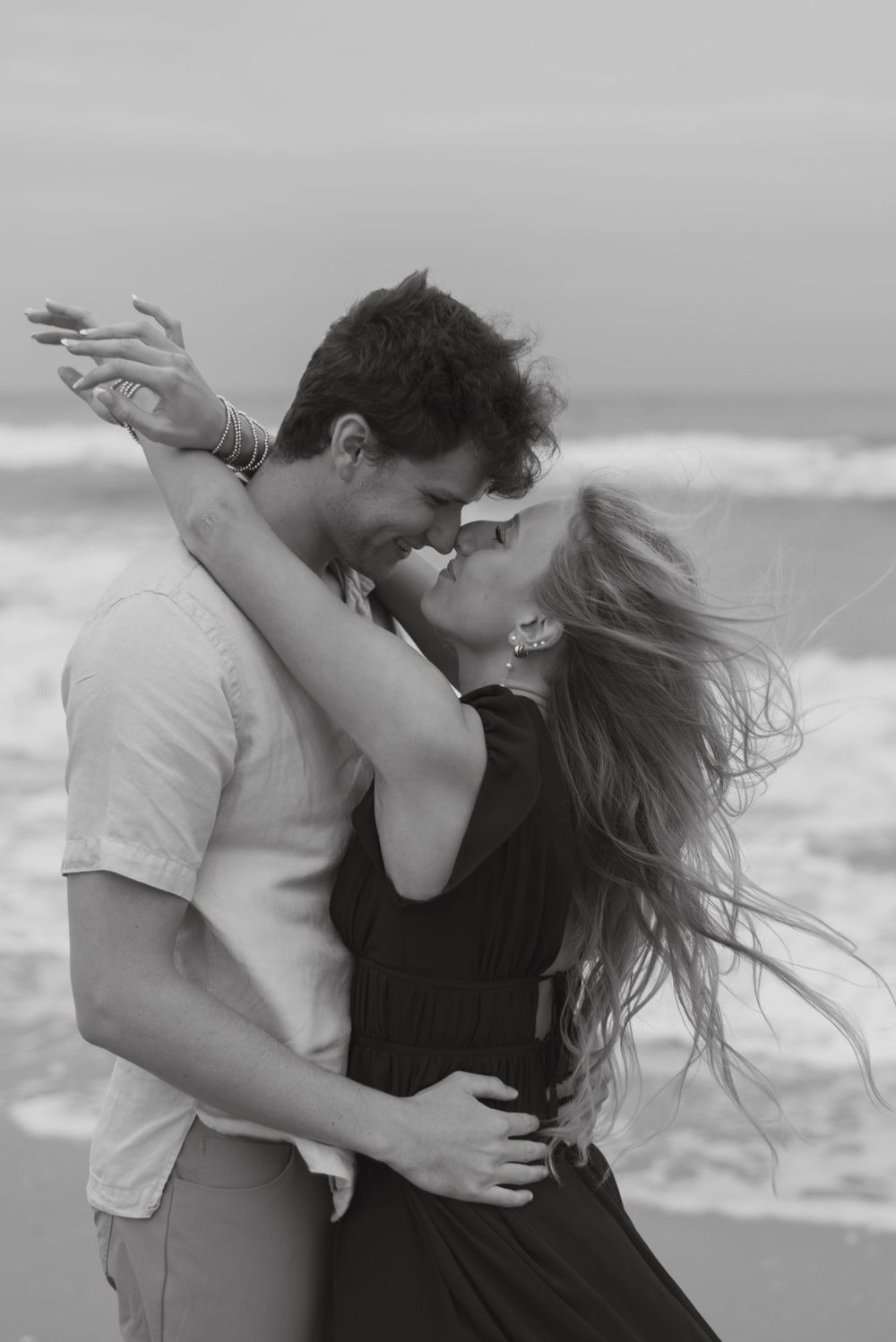 couple holding each other nose to nose at the beach