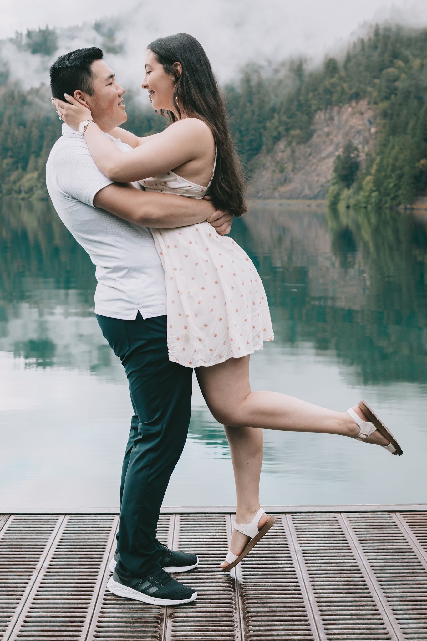 A couple man and woman on a dock at Lake Crescent he is lifting her up