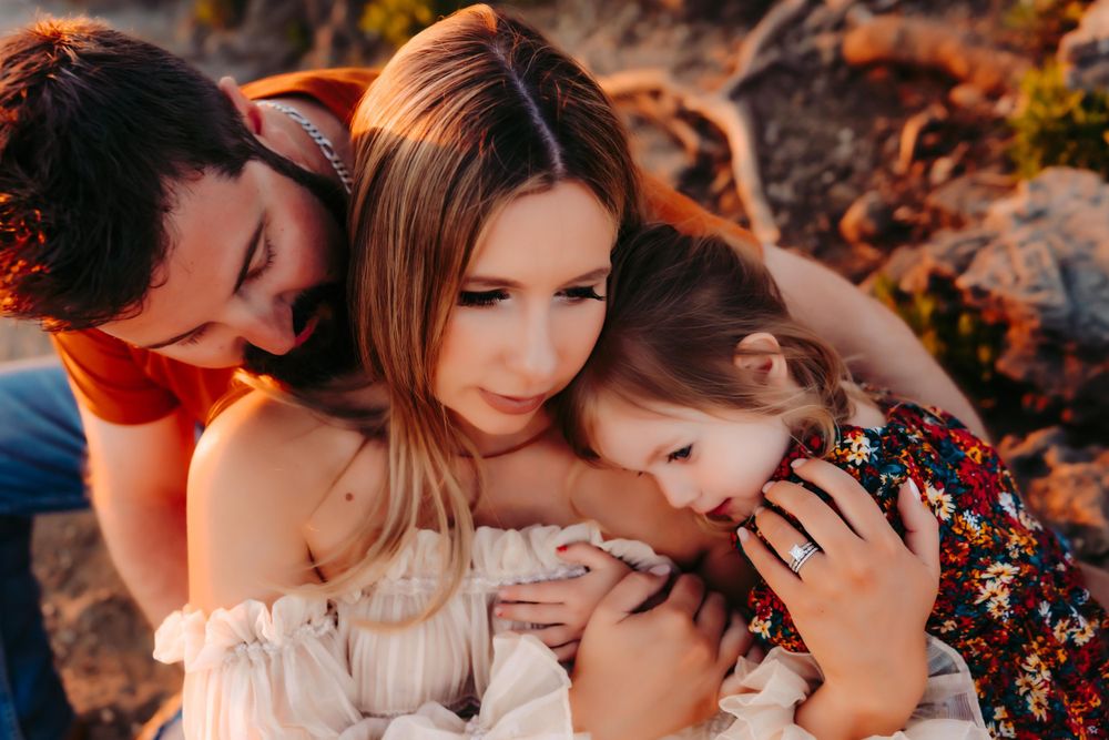An intimate family moment captured during golden hour on rocky terrain.