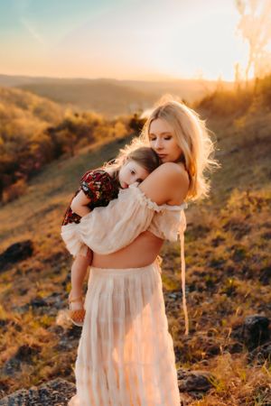 A touching sunset moment between two people in white flowy clothing on a golden hillside.