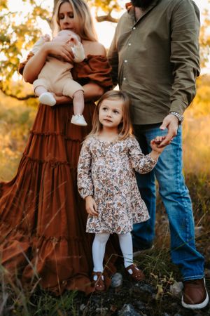 Family in coordinated autumn outfits posing together at sunset.