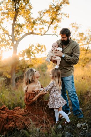 A family shares a tender moment together in a golden autumn field at sunset.