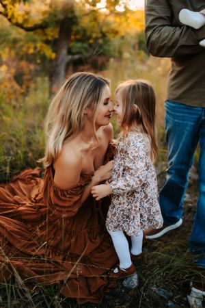 Intimate family moment captured in warm autumn sunlight with flowing brown dress.