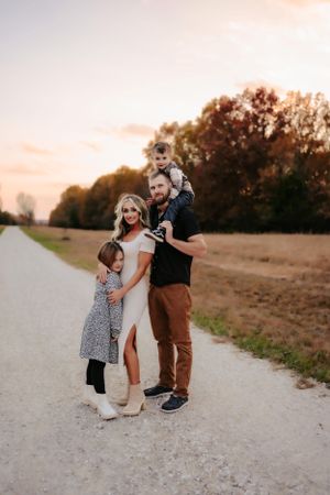 Family standing on a country path during sunset with golden light.