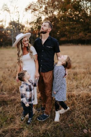 Candid family moment in golden field with casual attire during sunset.