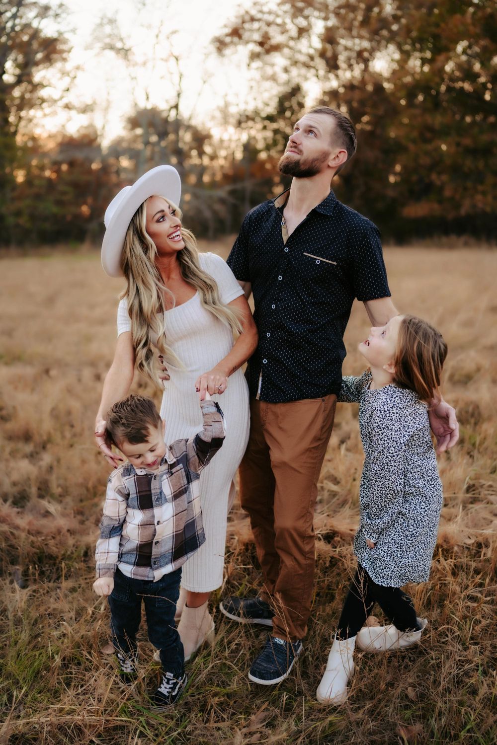 Family portrait in autumn field with casual western style clothing at sunset.