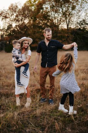 Family enjoying playful moments together in a sun-drenched field at sunset.