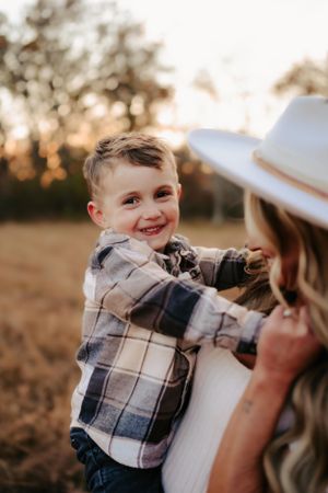 Candid outdoor portrait showing a joyful smile and plaid shirt on little one during golden hour.