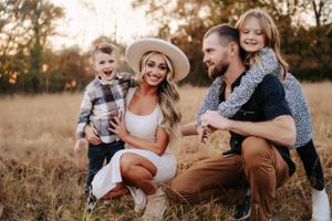 Family portrait in a golden field during sunset with casual autumn attire.