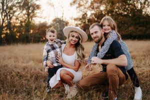 Casual outdoor family photo session in a rustic field during golden hour.