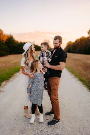 Family gathered together on a country road during sunset.