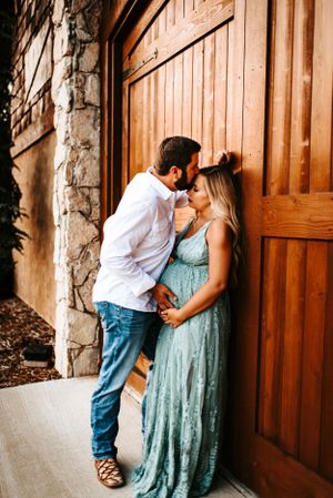 Intimate couple portrait against wooden door with stone column details.