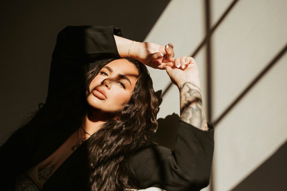 Artistic portrait with dramatic window shadows and black clothing.