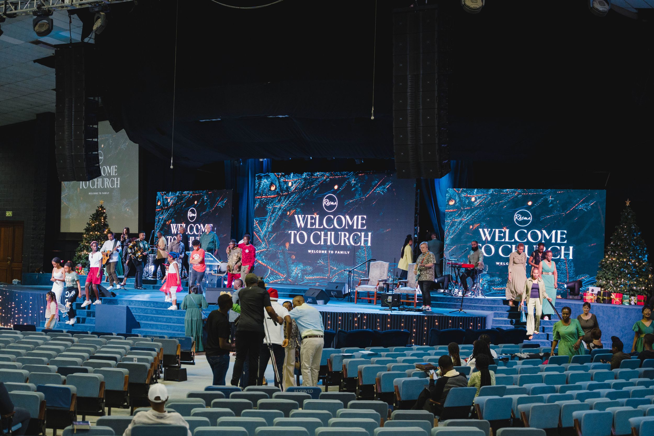 Crowd gathering at outdoor concert venue with welcome sign and seating.