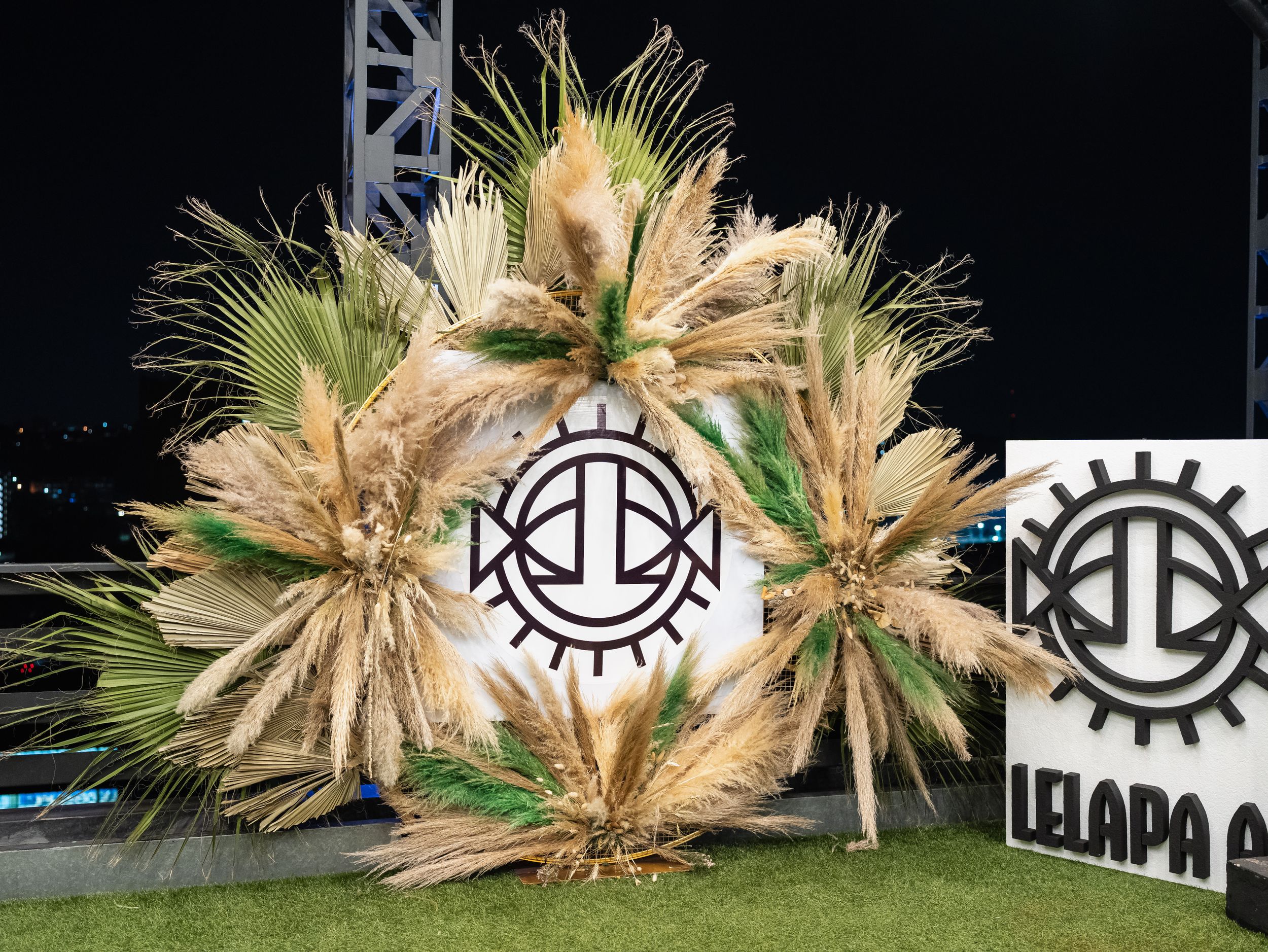 Large decorative wreath made of dried palm fronds with industrial logo design in the center.
