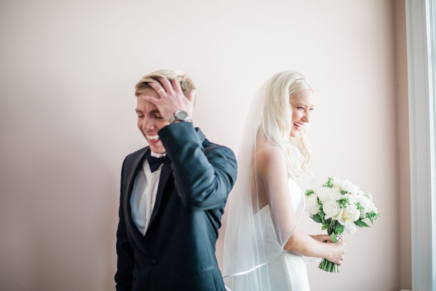 A playful first look moment between newlyweds in a minimalist setting.