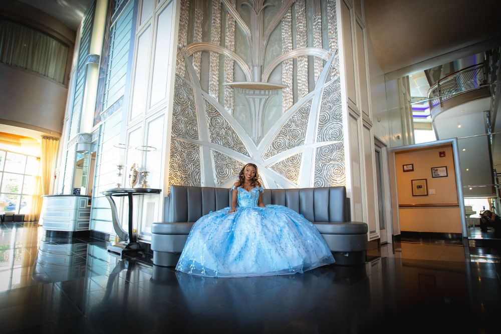 Dramatic wide shot of blue ballgown in modern architectural space with tall windows.