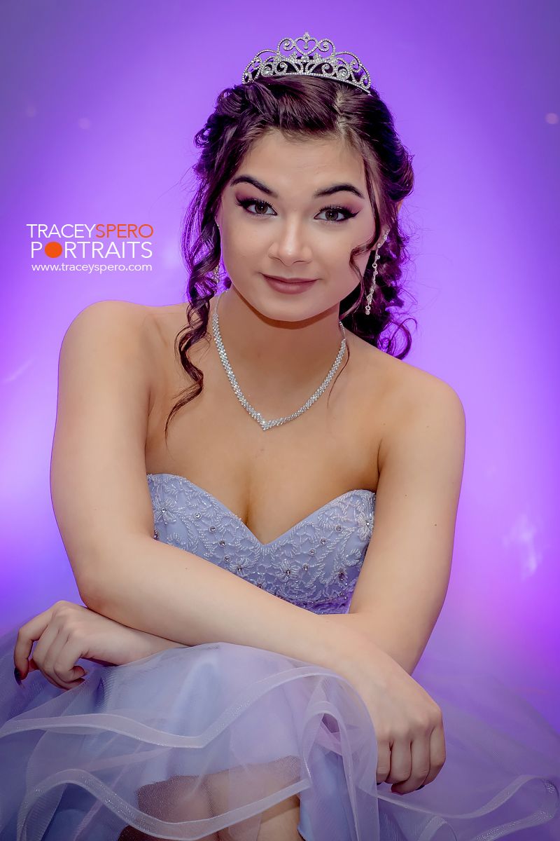 Studio portrait with purple background showcasing formal gown and crystal accessories.