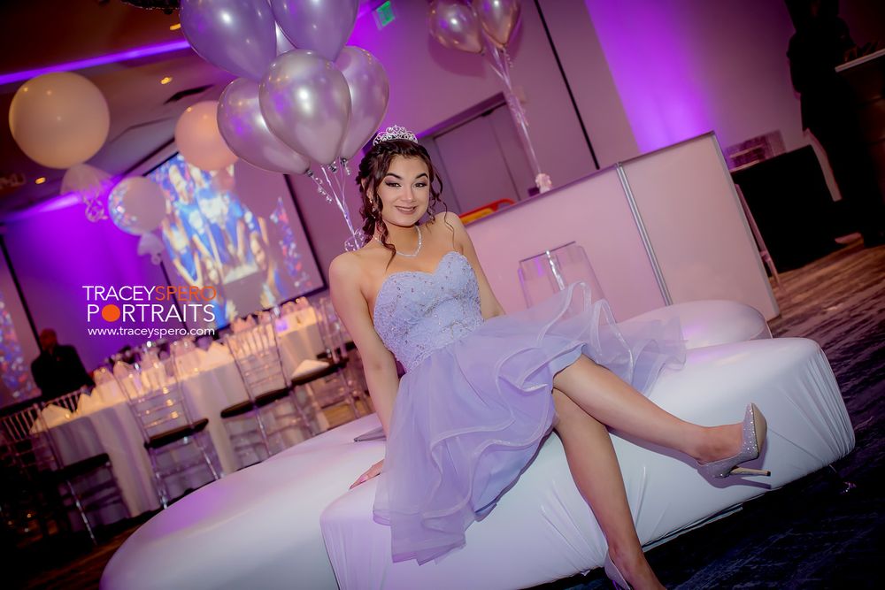 Celebratory scene with balloons and formal attire in purple-lit event space.